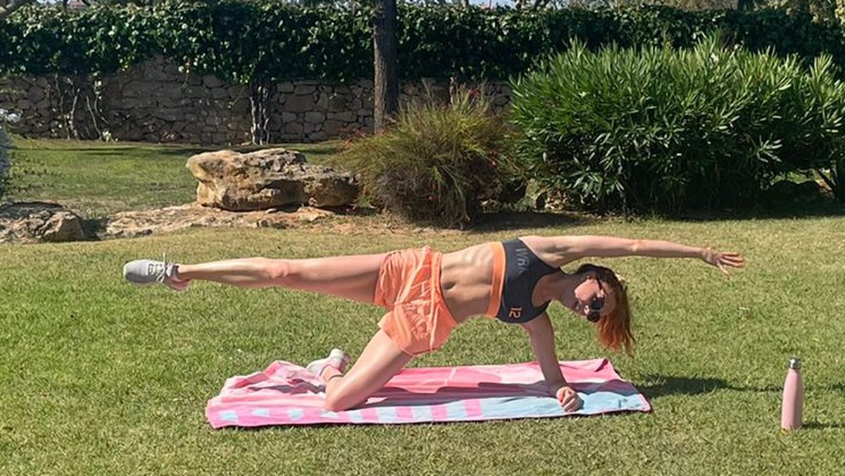 Side plank with one leg raised, on a towel in a sunny garden